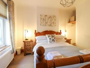 a bedroom with a large bed with a wooden headboard at Poppy Cottage in Ashbourne