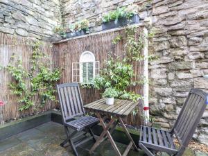 2 chaises et une table en bois sur la terrasse dans l'établissement Poppy Cottage, à Ashbourne