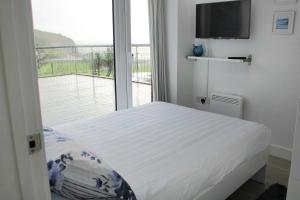 a bedroom with a bed and a large window at May View - Luxury Sea View Apartment - Millendreath, Looe in Looe