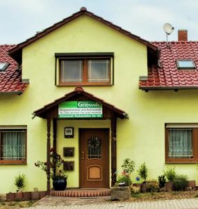 ein gelbes Haus mit einem grünen Schild über der Tür in der Unterkunft Pension Haus Germania in Erfurt