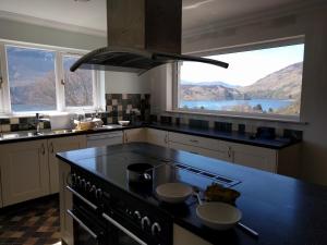 a kitchen with a stove and a large window at Bunloyne in Sallachy