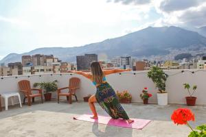 Eine Frau, die Yoga auf dem Dach eines Gebäudes macht. in der Unterkunft Maywa City Center in Quito