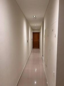 a hallway with white walls and a wooden door at DEPTO EN AV ROCA PARA HASTA 4 PERSONAS - Edificio MIRÓ1 in Santiago del Estero