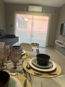 a dining room with a table with plates and wine glasses at DEPTO EN AV ROCA PARA HASTA 4 PERSONAS - Edificio MIRÓ1 in Santiago del Estero