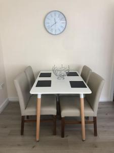 a dining room table with chairs and a clock on the wall at Winter Gardens North Pier Home in Blackpool