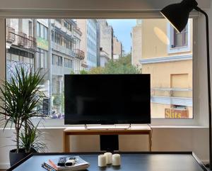 a flat screen tv sitting on a table in front of a window at Mosaikon Guesthouses #Aiolou Str in Athens