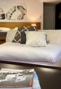 a bed with white sheets and pillows and a magazine at Mosaikon Guesthouses #Aiolou Str in Athens