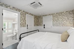 a white bedroom with a bed and a bathroom at The Stirrup House by Pattio in Miami