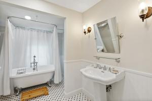 a white bathroom with a sink and a tub and a mirror at The Stirrup House by Pattio in Miami