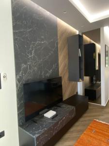 uma sala de estar com televisão e uma parede de mármore preto em Luxury Apartment em Akrata