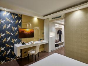 a dressing room with a desk and a tv on a wall at Winter Garden Hotel Bergamo Airport in Grassobbio