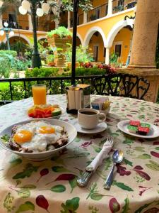 a table with a plate of eggs and fruit on it at Hotel Caribe Merida Yucatan in Mérida