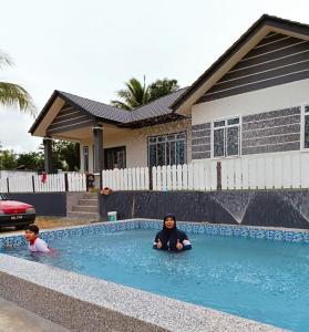 a woman and a child sitting in the water in a swimming pool at Homestay Bendang Hilir in Kuala Nerang