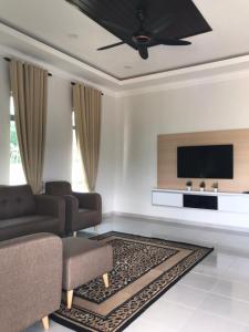 sala de estar con sofá y TV de pantalla plana en Homestay Bendang Hilir, en Kuala Nerang