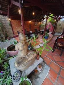 Una estatua de una mujer sentada junto a una fuente. en Soben Cafe Guesthouse & Restaurant en Siem Reap