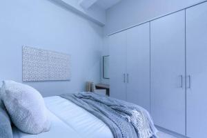 a white bedroom with a bed and white cabinets at Modern 1 bedroom apartment in Braamfontein Werf in Johannesburg