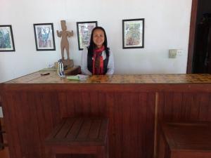 a woman is standing behind a wooden counter at Arun Mekong Guesthouse in Kratie