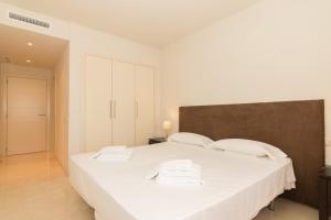 1 dormitorio con 1 cama blanca grande y 2 toallas en 2214-Modern apt with private beach, en Estepona