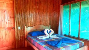 dos cisnes sentados en una cama en una habitación en Encanto Lodge en Drake