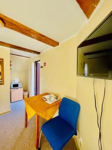 a room with a table and a blue chair and a television at Express Guest House in Klaipėda
