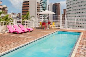 uma piscina com cadeiras cor-de-rosa e uma mesa num edifício em D8 Hotel Express em Fortaleza