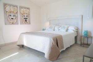 1 dormitorio blanco con 1 cama blanca y 2 pinturas en CORALLI DEL PLEMMIRIO en Siracusa