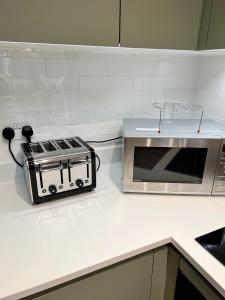 a kitchen counter with a toaster and a microwave at Lovely Super Luxury One Bed Apartment 216 in Luton