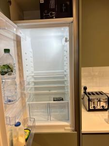 an open refrigerator with a bottle of water and milk at Lovely Super Luxury One Bed Apartment 216 in Luton