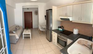 uma cozinha com um frigorífico e um sofá num quarto em Aristea’s place Askeli em Poros