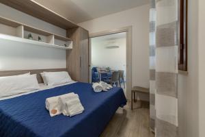 una camera da letto con un letto blu e asciugamani di I Tre Golfi - Via Salvatore Quasimodo a San Vito lo Capo