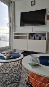 a living room with a table and a tv at May View - Luxury Sea View Apartment - Millendreath, Looe in Looe