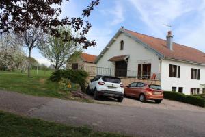 two cars parked in front of a white house at Gîte Les Hirondelles in Plombières-les-Bains