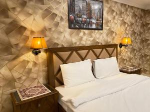 a bedroom with a bed with two night stands and two lamps at Arya Hotel Islamabad in Islamabad