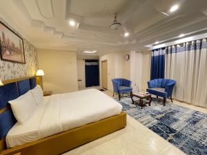 a bedroom with a bed and two blue chairs at Arya Hotel Islamabad in Islamabad +61 photos