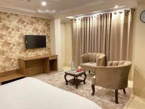 a hotel room with a bed and two chairs and a tv at Arya Hotel Islamabad in Islamabad
