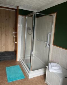 y baño con ducha de cristal y alfombra azul. en York Cottage a period character 2 bedroom cottage en Snettisham