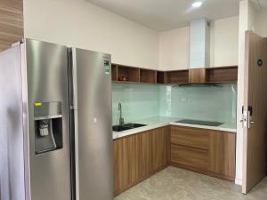 a kitchen with a stainless steel refrigerator and wooden cabinets at Whisky The Light Phú Yên in Tuy Hoa