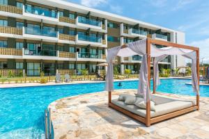 einem Hotelpool mit einem Bett vor einem Gebäude in der Unterkunft Mana Beach Experience Muro Alto por Brevelar in Porto De Galinhas