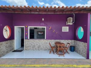 una casa con una pared púrpura, una mesa y sillas en BARREIRINHAS CHALÉ 12 PORTO DOS LENÇÓIS, en Barreirinhas