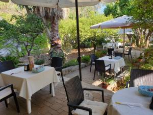 een restaurant met tafels en stoelen en een parasol bij B&B Pittoresco in Specchia