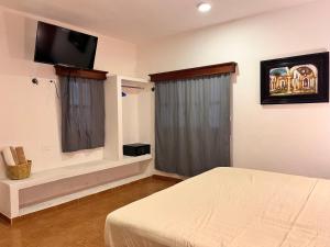 1 dormitorio con 1 cama y TV de pantalla plana en Tumben Kuxtal Tulum, en Tulum
