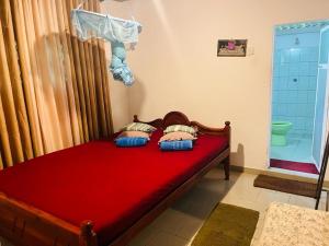 - une chambre avec un lit rouge et une douche dans l'établissement Sinharaja Tour Hostel, à Deniyaya