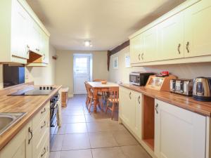 a kitchen with white cabinets and a table in it at Ynys in Dyffryn