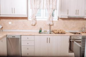 a kitchen with white cabinets and a sink and a window at Villa Sea Breeze in Karpathos +21 photos