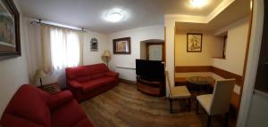 a living room with a red couch and a tv at Hotel Casa Escolano in El Pueyo de Jaca
