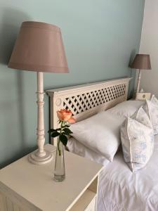 a vase with a flower on a table next to a bed at Constantia cottage- Warblers Nest in Cape Town