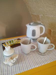 2 tazas y una tetera sobre una mesa en Casina Rossa di Pietrafitta, en Casarano