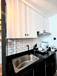 a kitchen with a sink and white cabinets at Antara-QueenBed-Balcony-HotShower-WorkCoffee Station-FullKitchen in Talisay