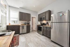 una cocina con nevera de acero inoxidable y armarios de madera en HostWise Stays - The Edmond - Bloomfield Apartment in a great location!, en Pittsburgh