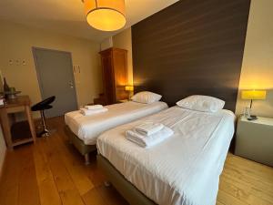 Cette chambre d'hôtel comprend 2 lits avec des draps blancs. dans l'établissement Race & Rooms, à Francorchamps